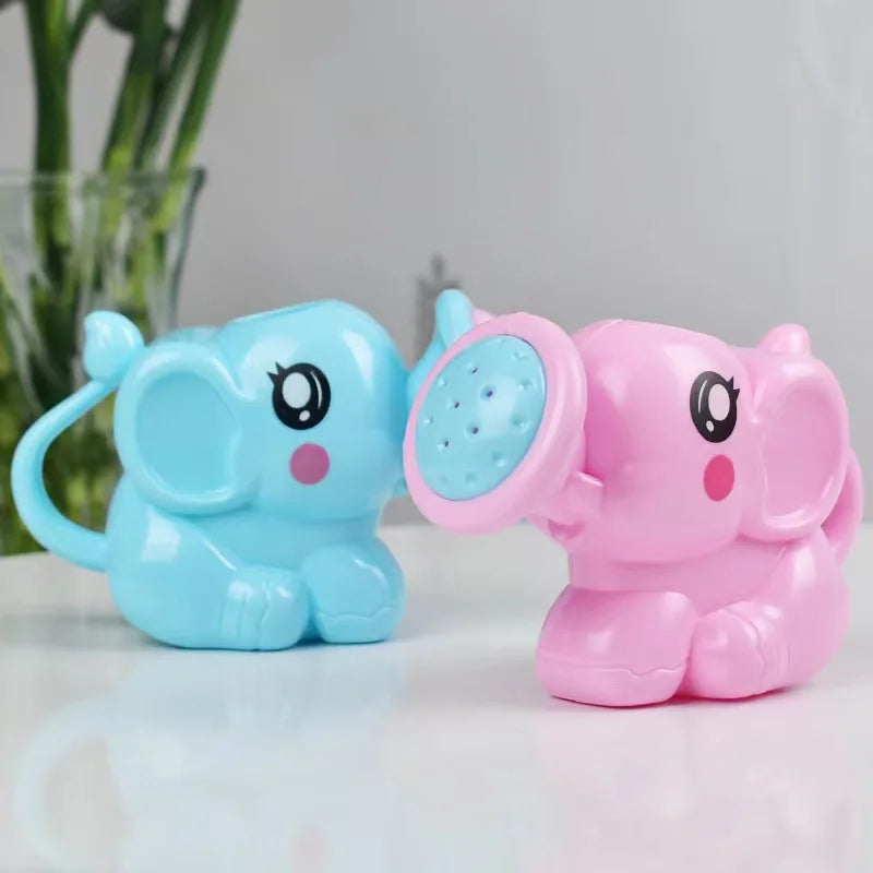 Regaderas de elefante azul y rosa sobre una mesa junto a una planta