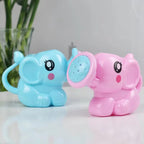 Regaderas de elefante azul y rosa sobre una mesa junto a una planta