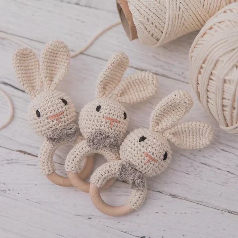 Tres sonajeros de conejito de crochet junto a ovillos de hilo de algodón