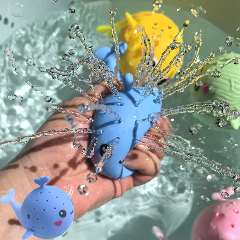 Mano apretando la ballenita azul mientras suelta chorritos de agua