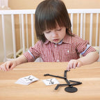 Niña sentada a la mesa copiando una pose con el muñeco articulado