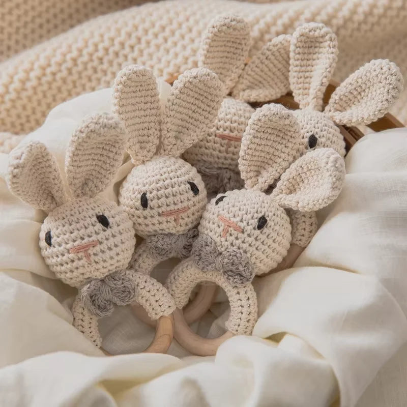 Varios sonajeros de conejito de crochet con aro de madera sobre una manta blanca