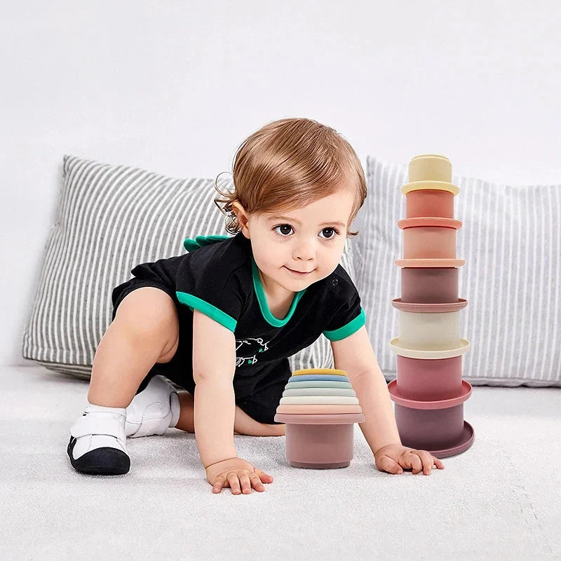 Bebé gateando hacia una torre de vasos apilables