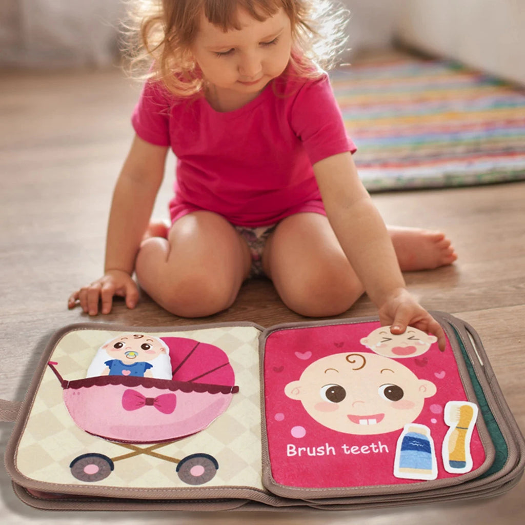 Niña sentada en el piso jugando con el libro sensorial de fieltro abierto