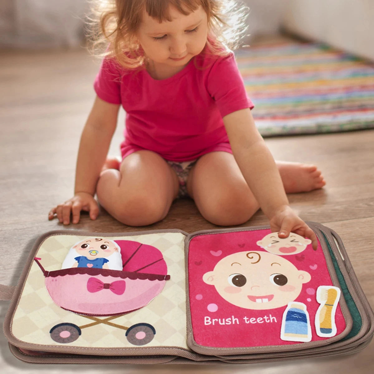 Niña sentada en el piso jugando con el libro sensorial de fieltro abierto